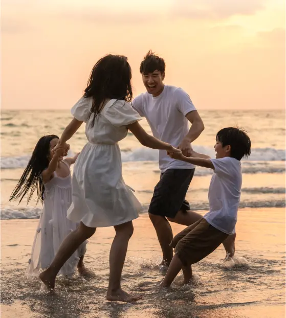 A family holding hands and playing on a beach at sunset
