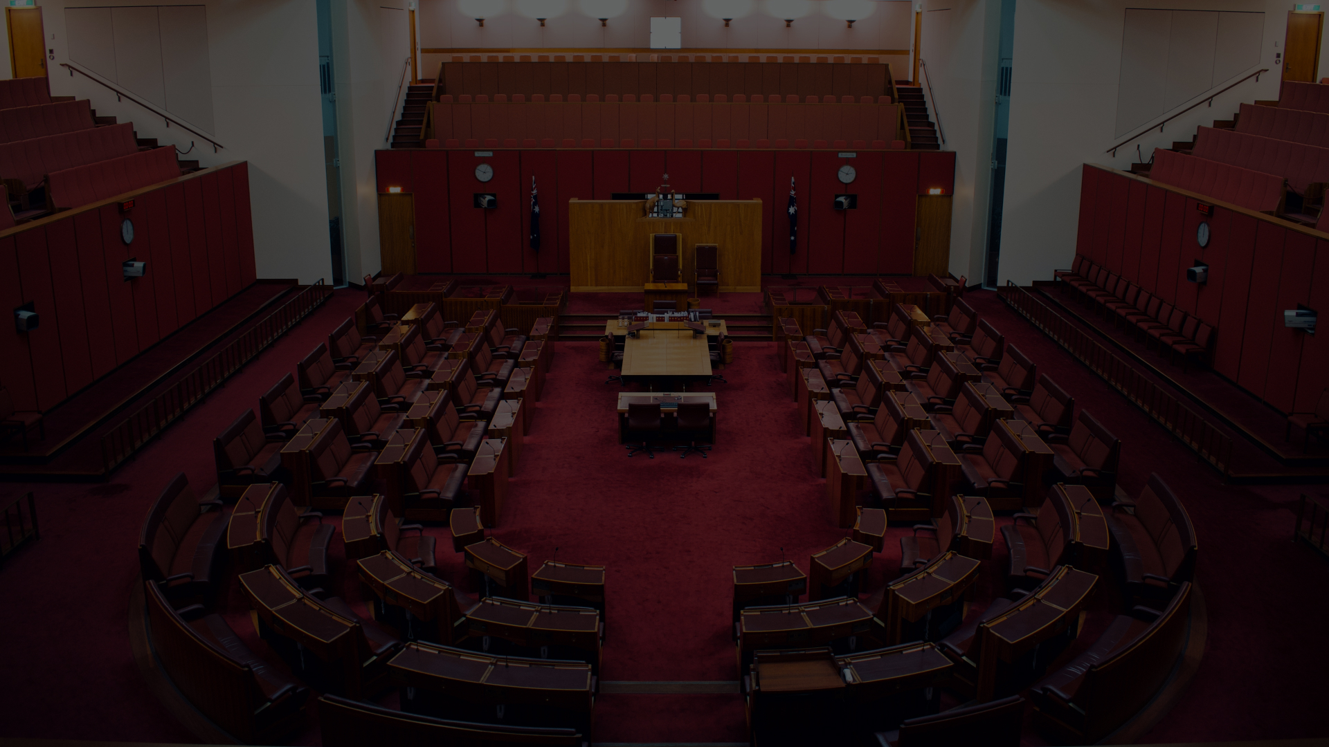 A parliamentary chamber with rows of desks and red seats