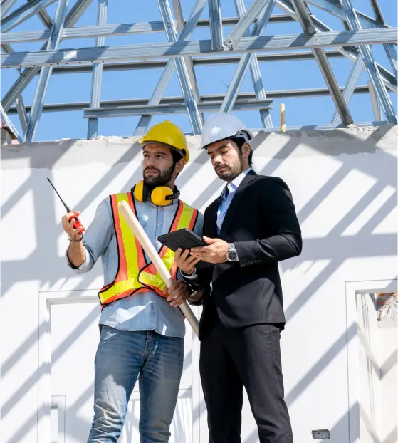 Two construction workers with hard hats discuss plans