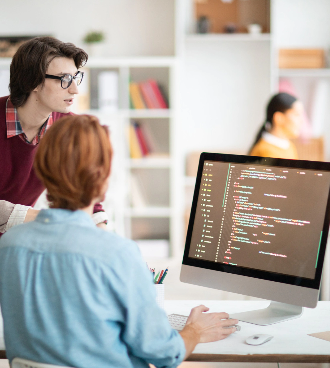 Two people collaborating for digital marketing services at a computer with code on screen
