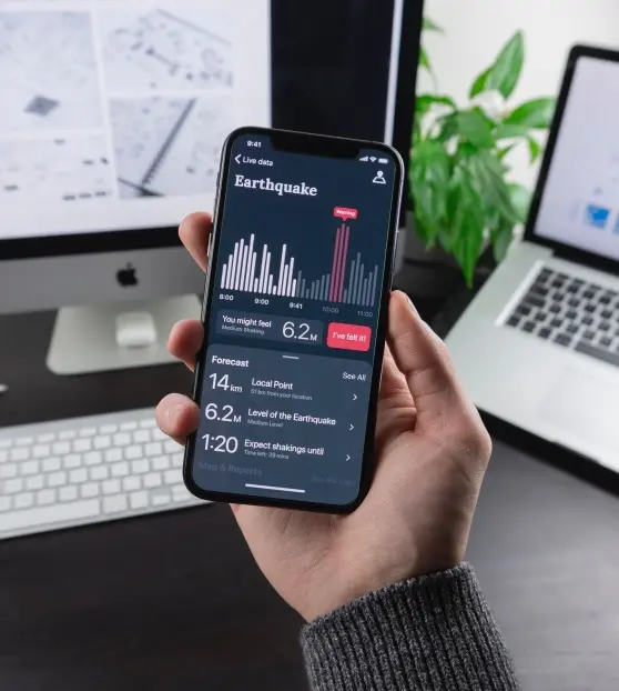 Hand holding smartphone displaying earthquake data