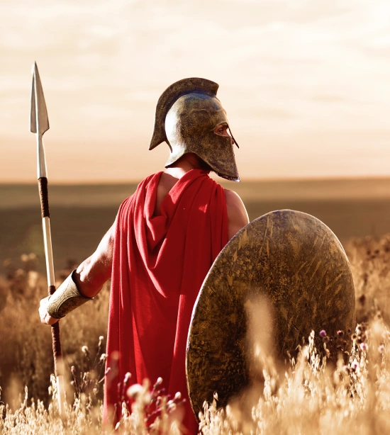 Spartan warrior in armor with spear and shield at sunset