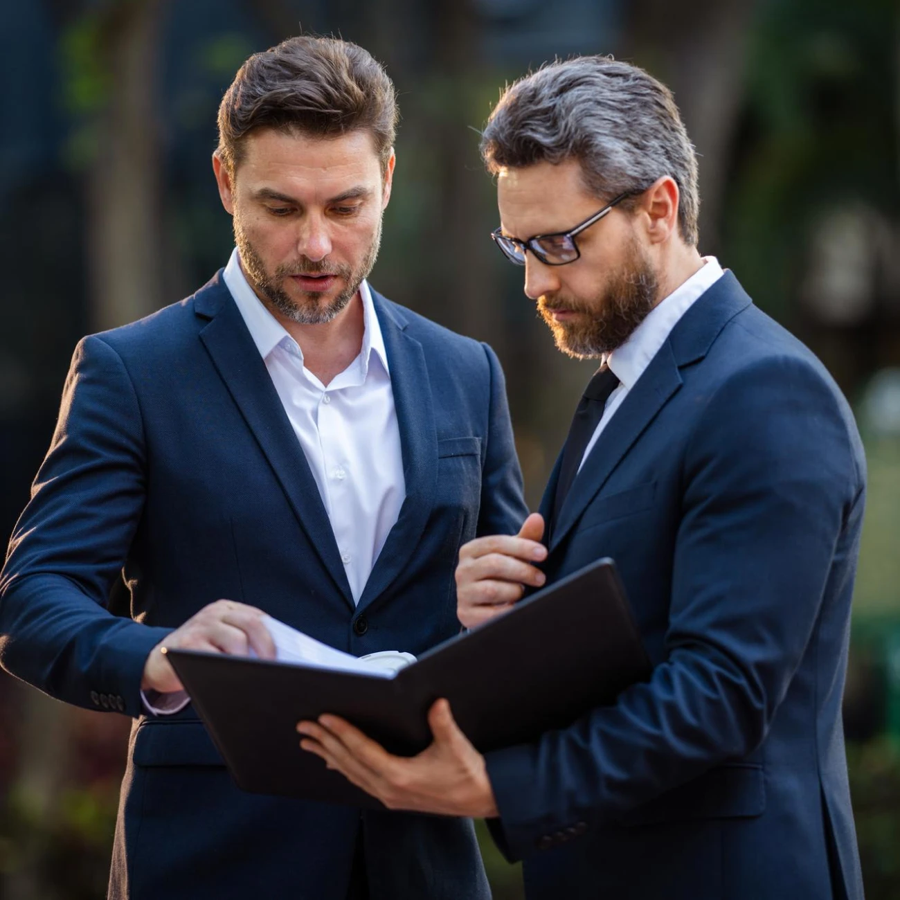 Two business professionals discussing documents in formal attire